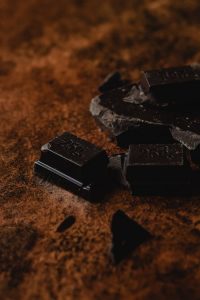 Photo de carré de chocolat noir posée sur de la poudre de cacao